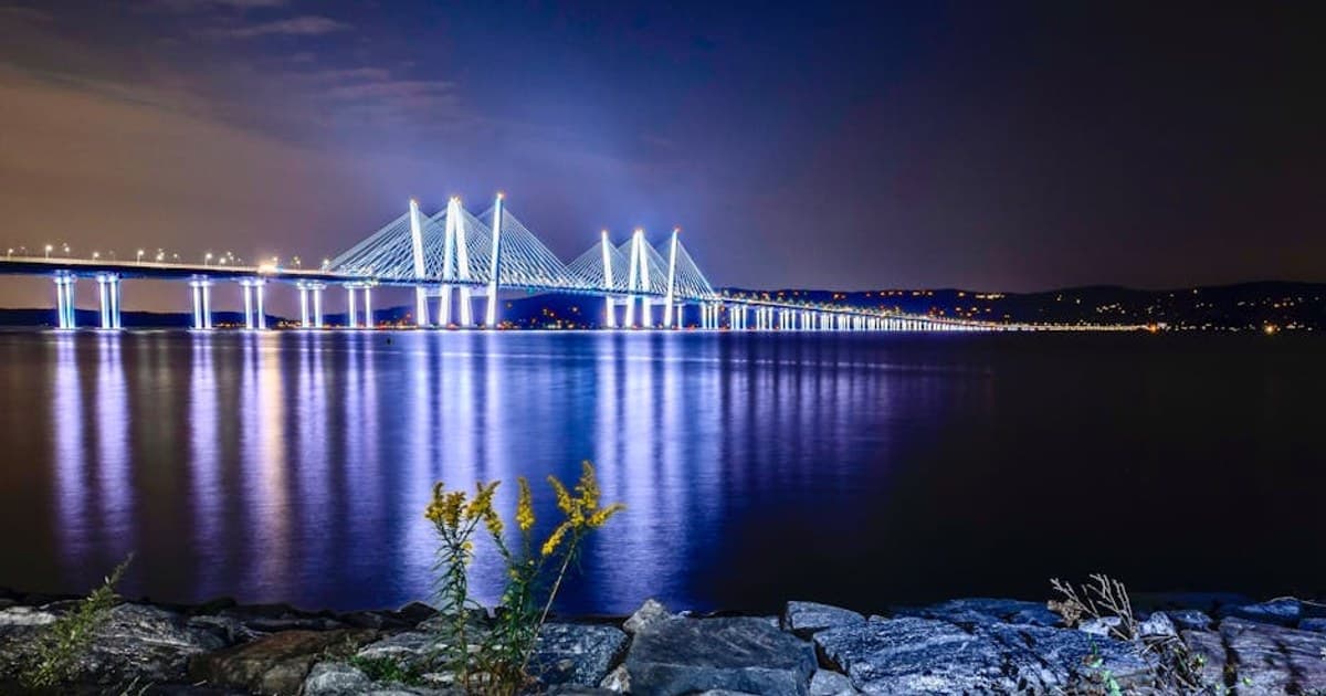 Stunning night view of the illuminated Tappan Zee Bridge over the Hudson River with reflections on the water.