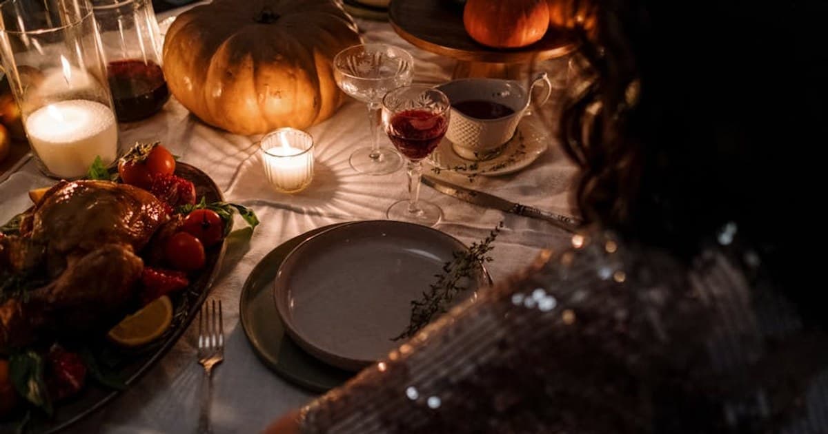 Intimate Thanksgiving dinner setup with candles, turkey, and elegant table setting.