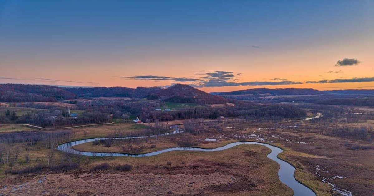 Aerial view of a winding river through autumn fields in Tell, Wisconsin at sunset.