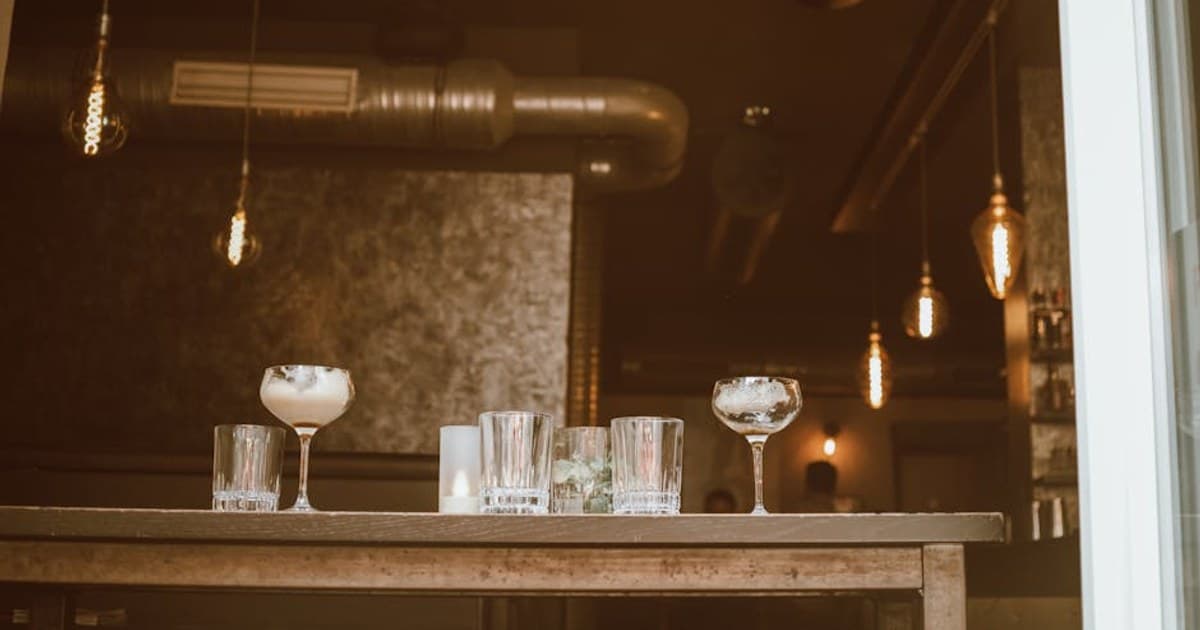 Stylish cocktail bar with industrial design in Cologne, featuring empty glasses and elegant lighting.