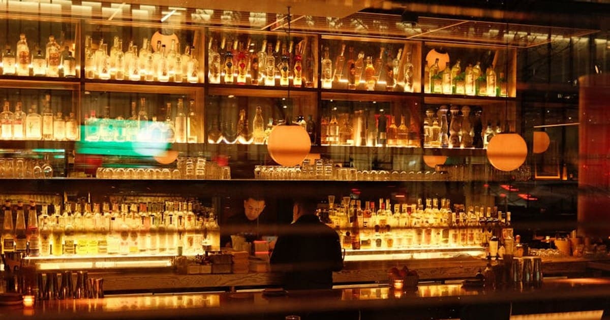 Warm and inviting bar interior in New York, featuring illuminated shelves of bottles and soft ambient lighting.
