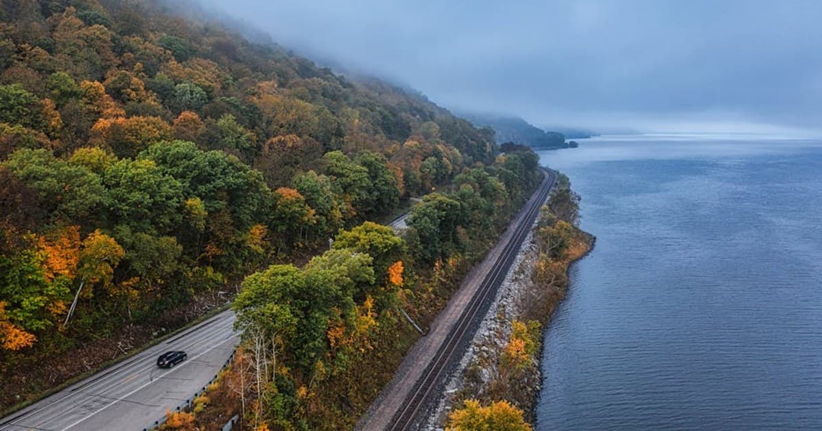 Scenic aerial view of a foggy autumn landscape with a road and railway along a lake in Minnesota.