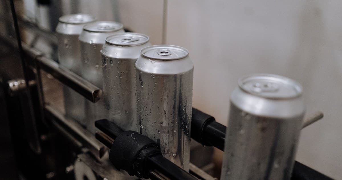 Close-up of aluminum cans with water droplets on a production line, showcasing industrial beverage processing.