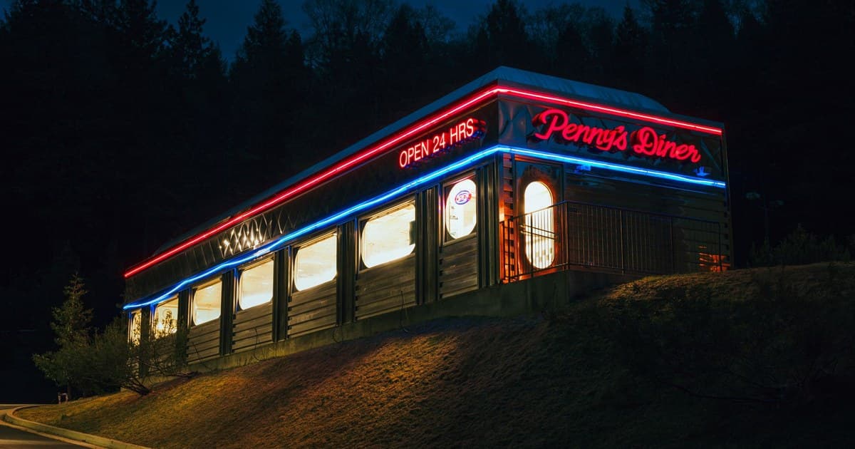 Diner exterior with vibrant neon lights at night, offering a retro ambiance.